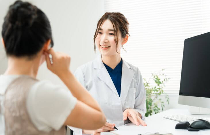 A doctor consulting a woman with a bump on her ear caused by piercing