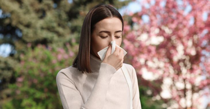 A young woman having symptoms of seasonal allergy when walking through the park