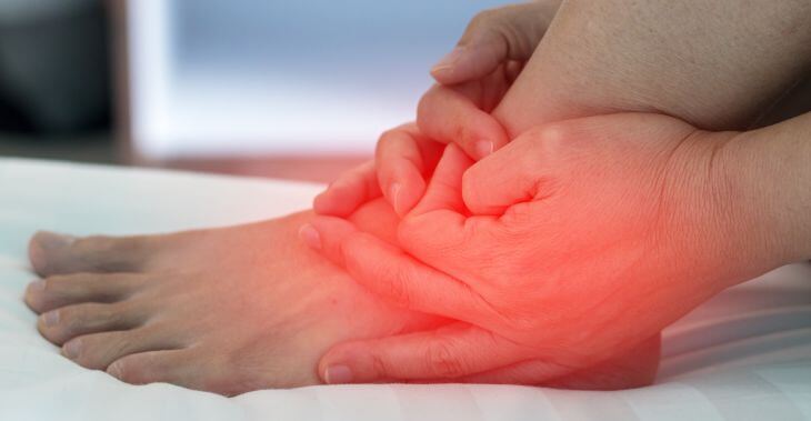 A man touching his painful ankle