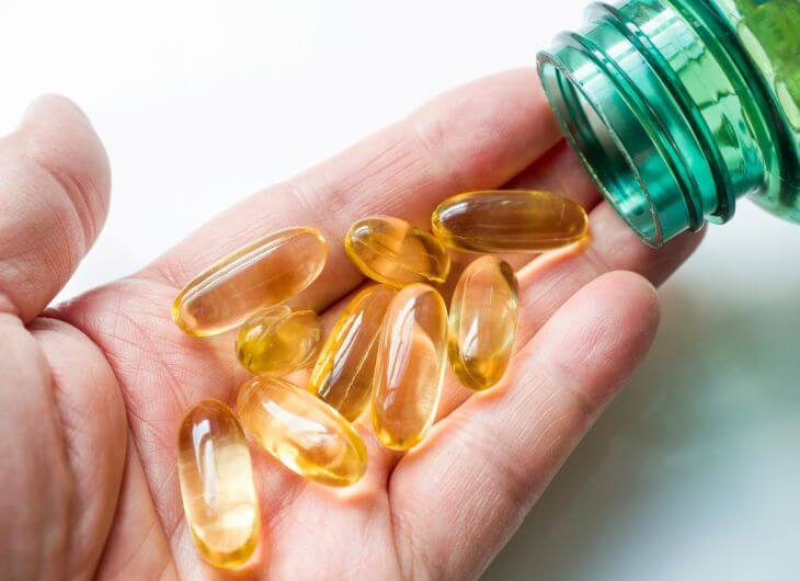 A hand of a person taking vitamin D supplement pills