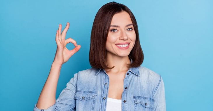 Confident beautiful youngish-looking woman with a perfect smile showing OK with her fingers