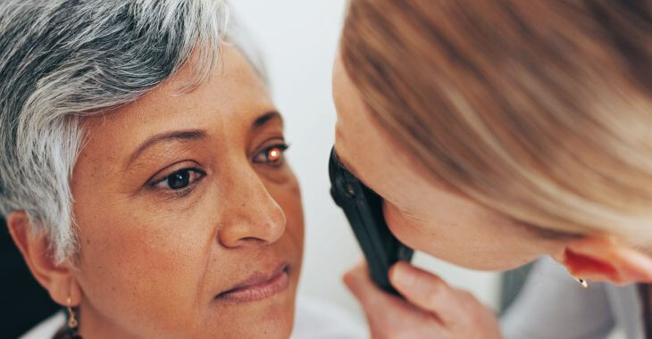 A doctor examining elderly woman's eyes