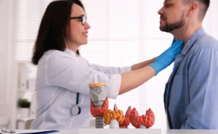 Endocrynologist examining man's thyroid gland