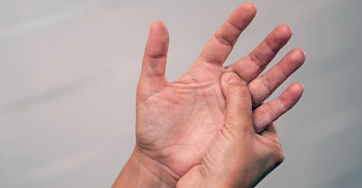 Man feeling numbness in a hand massaging his plam and fingers