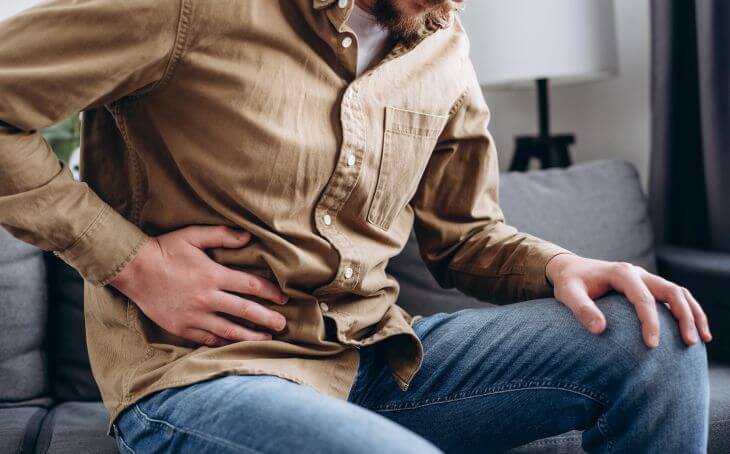 A man experiencing pelvic pain sitting on a sofa 