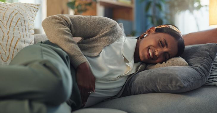 Woman suffering from severe pelvic pain lying on a couch