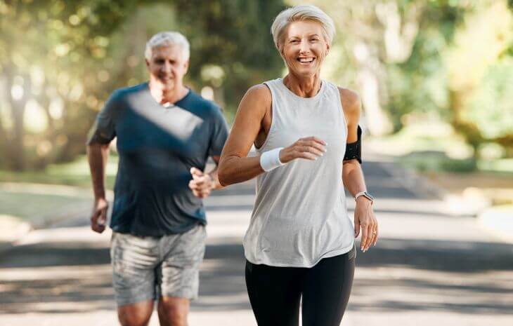 Happy active senior woman and man running in a park