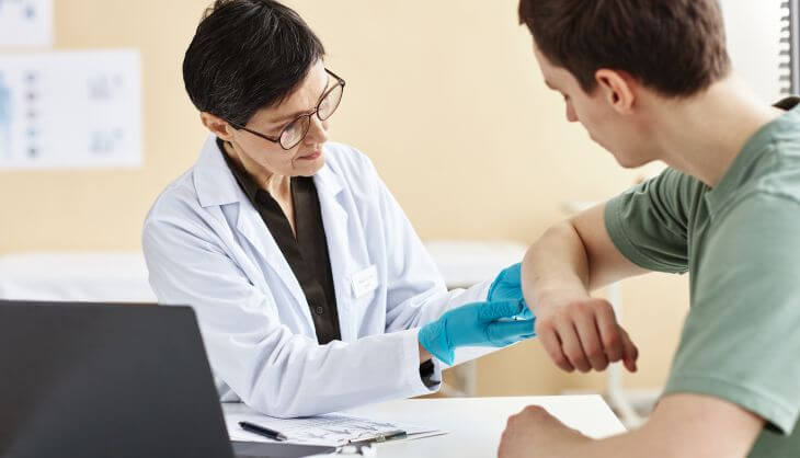 a dermatologist examining skin rash on males forearm